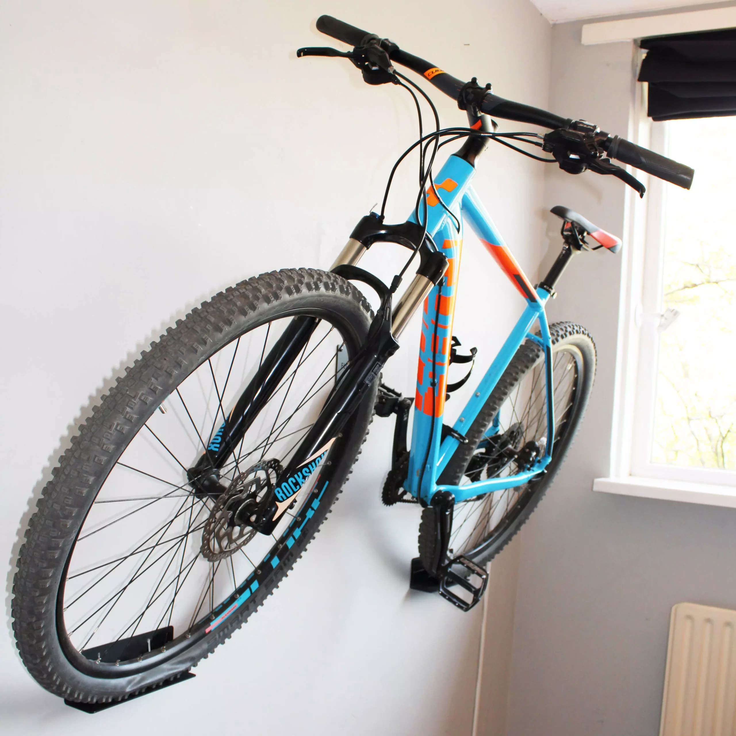 Blauwe Mountainbike opgehangen op de muur aan een Flowter trapper hanger